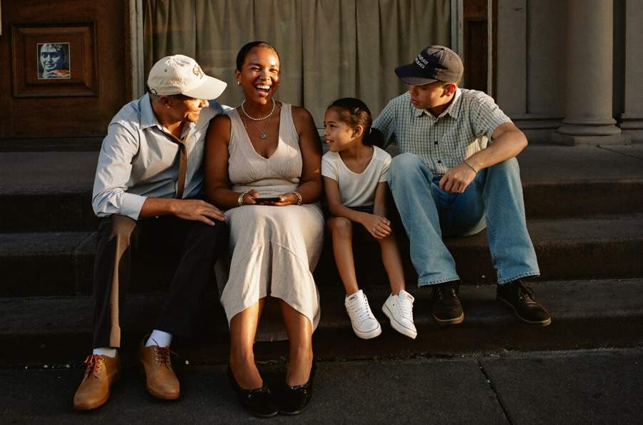 A family of four sitting together on the front steps of a brownstone in Queens.